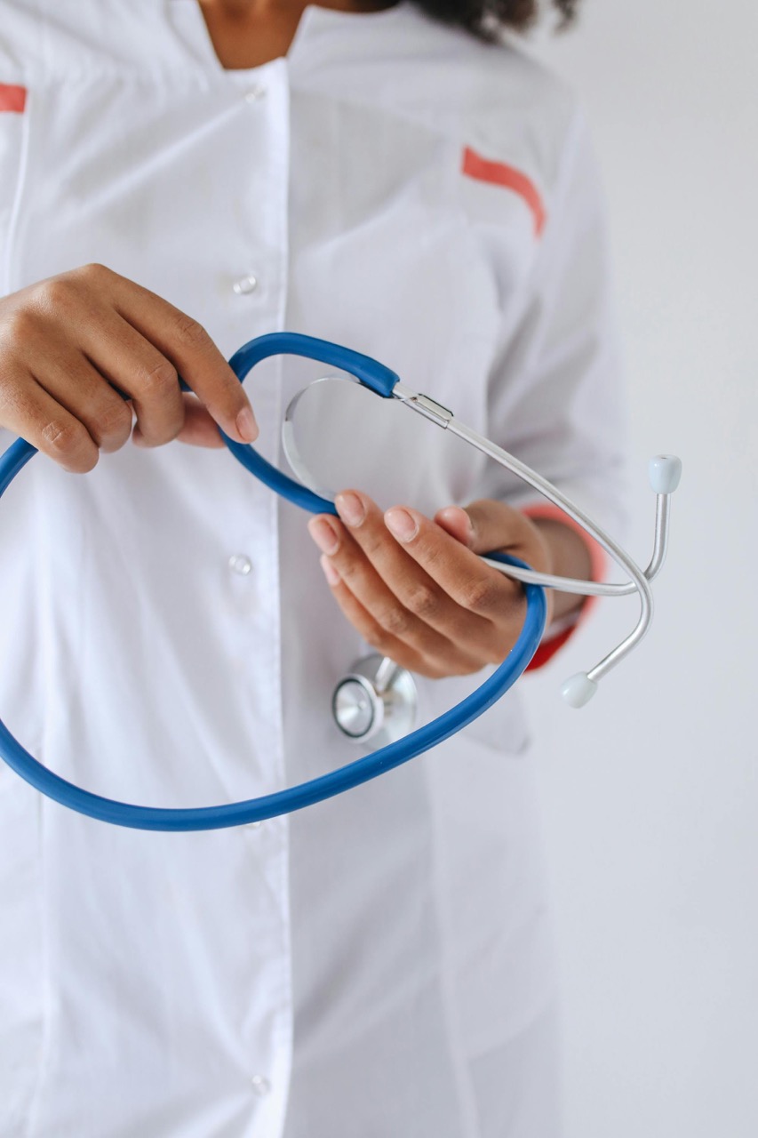 Person in a white coat holding a blue stethoscope with both hands, symbolizing trust and care—qualities essential in lending and investing.