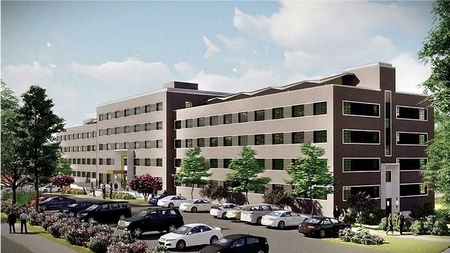 Modern four-story apartment building ideal for investing, with parked cars and trees in front under a partly cloudy sky.