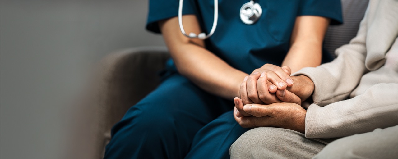 A healthcare worker gently holding the hand of an elderly patient, offering comfort and support.