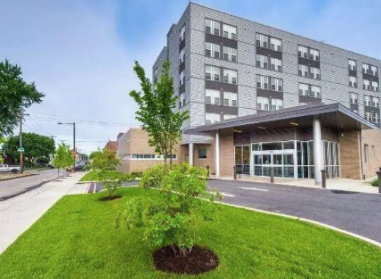 Modern multi-story LIFE Center building with large windows, an entrance canopy, and a landscaped green lawn with small trees.
