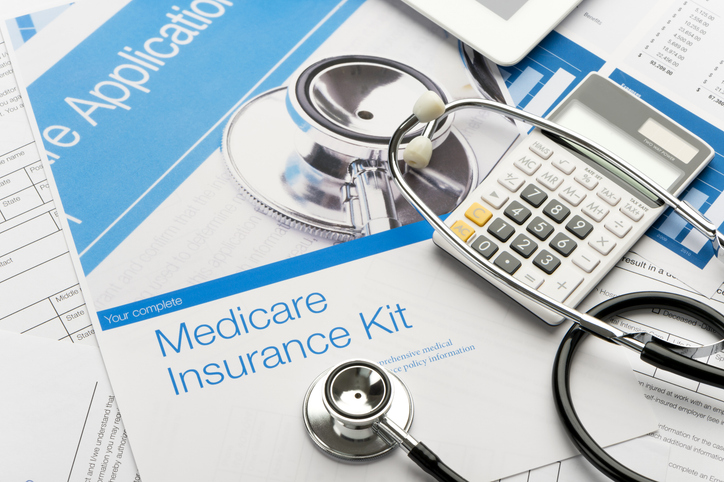 Medicare insurance kit with papers, a stethoscope, and a calculator on a desk.